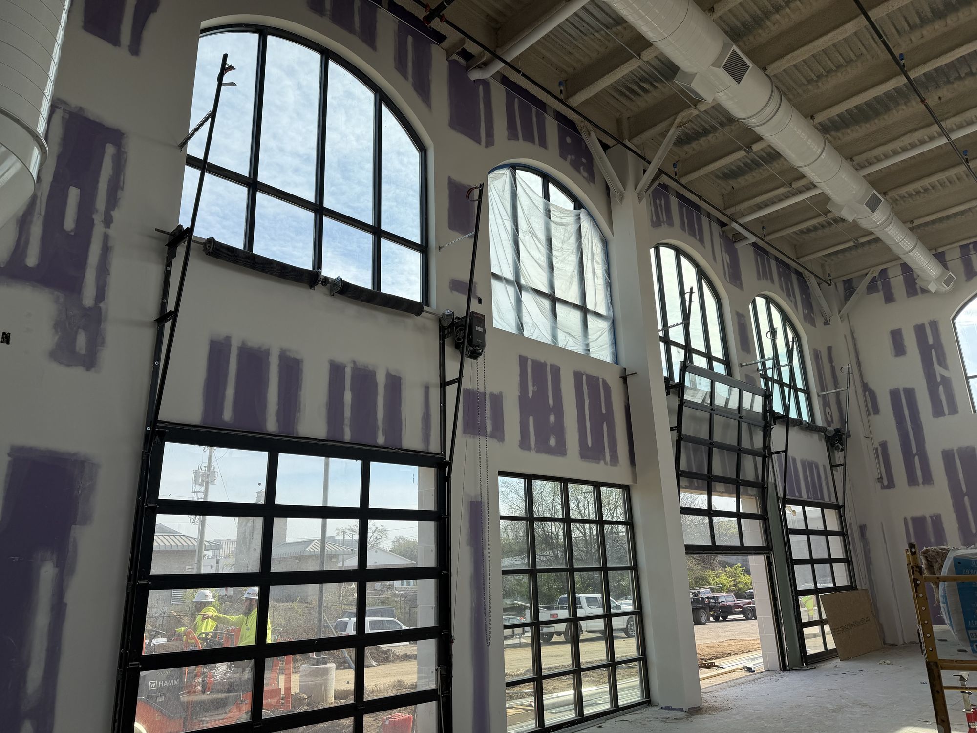 Arched windows and roll-up glass doors in a building under construction